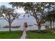 Peaceful view of the lake and boat dock framed by mature trees and manicured lawn at 415 Carman Dr, Leesburg, FL 34748