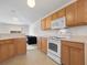 Functional kitchen featuring wood cabinets, white appliances, and seamless flow to the living area at 464 Dominish Estates Dr, Apopka, FL 32712