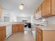 Bright kitchen with wood cabinetry, white appliances, and a view into the adjacent living space at 464 Dominish Estates Dr, Apopka, FL 32712