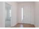 Bright entryway with wood-look flooring, white door, and glimpse of a carpeted room through an open doorway at 5097 Grand Teton Ct, Deland, FL 32724