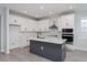 Modern kitchen with a gray island, white cabinets, stainless steel appliances, and wood-look flooring at 5097 Grand Teton Ct, Deland, FL 32724