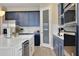 Modern kitchen featuring navy blue cabinets, white quartz countertops, stainless steel appliances, and a farmhouse sink at 5306 Marshelder St, Apopka, FL 32712