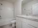 Bright bathroom featuring a white tub-shower, toilet, and vanity with granite countertop at 5391 Dragonfly Dr, Wildwood, FL 34785