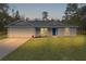 Charming single-story home featuring a well-maintained lawn and a bright blue front door at 68 Malauka Pass Crse, Ocklawaha, FL 32179