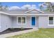 Inviting front porch with blue door, new landscaping, and neutral gray paint at 68 Malauka Pass Crse, Ocklawaha, FL 32179