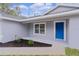 Inviting front porch with blue door, new landscaping, and neutral gray paint at 68 Malauka Pass Crse, Ocklawaha, FL 32179