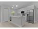 Modern kitchen with stainless steel appliances, island, and bright white cabinets at 68 Malauka Pass Crse, Ocklawaha, FL 32179