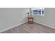 Bright bedroom corner featuring wood-look floors, a charming side table, and a window for natural light at 730 Royal Palm Ave, The Villages, FL 32159