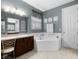 Bathroom featuring a tub, large mirror, vanity, and a separate door to the toilet at 887 Daisy Hill Ct, Apopka, FL 32712