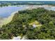 Scenic aerial view of a home nestled among trees with a lake in the backdrop, offering a blend of nature and tranquility at 9905 Skylark Ln, Groveland, FL 34736