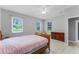 Bedroom with a wooden dresser, wooden bed with pink cover, and three bright windows at 9905 Skylark Ln, Groveland, FL 34736