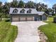 Large three-car garage with ample parking space and a well-maintained lawn, complemented by a small shed at 9905 Skylark Ln, Groveland, FL 34736