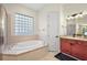 Bathroom showcasing a soaking tub, vanity sinks, and tiled flooring at 9930 Santa Barbara Ct, Howey In The Hills, FL 34737