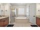 Bright bathroom featuring a jacuzzi tub, glass-enclosed shower, and double vanity sinks at 9930 Santa Barbara Ct, Howey In The Hills, FL 34737