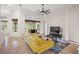 Living room showcases tile floors, ceiling fan, yellow sofa, and bright light from the windows at 9930 Santa Barbara Ct, Howey In The Hills, FL 34737