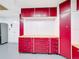 Organized garage featuring custom red cabinets and a pegboard wall, offering ample storage and workspace at 100 Grand Reserve Dr, Davenport, FL 33837