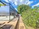 Covered patio visible from paver walkway surrounded by lush greenery and a screened enclosure at 100 Grand Reserve Dr, Davenport, FL 33837