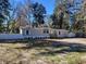 Charming single story home with a fenced yard, complemented by mature trees and blue sky at 100 Se 81St St, Ocala, FL 34480