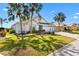 Charming single-story home featuring a well-manicured lawn, palm trees, and an attached two-car garage at 1044 Alcove Loop, The Villages, FL 32162