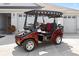 Burgundy and black golf cart parked in front of a white garage door at 1044 Alcove Loop, The Villages, FL 32162