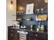 Modern wet bar with a wine cooler, glass shelving, stylish lighting, and elegant decor at 1044 Alcove Loop, The Villages, FL 32162