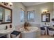 Bright bathroom with a central soaking tub, dual sinks, and decorative mirrors at 10909 Mattioda Rd, Groveland, FL 34736