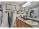 Bathroom features double sinks with wooden cabinets, framed mirror, and nautical decor at 10909 Mattioda Rd, Groveland, FL 34736