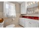 Bathroom featuring tiled walls, white vanity with red counter, and a bright mirror at 11820 Watts Ct, Tavares, FL 32778