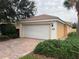 Close up of a single car garage featuring a brick driveway and manicured shrubbery at 11943 Iselle Dr, Orlando, FL 32827