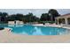 Community pool with a rounded zero entry wading area surrounded by chairs and tables at 11943 Iselle Dr, Orlando, FL 32827