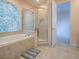 This bathroom has a soaking tub beneath a glass block window and a glass-enclosed shower at 16126 Bristol Lake Cir, Orlando, FL 32828