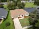 Aerial view of a well-maintained home featuring a manicured lawn, vibrant landscaping, and an attached garage at 16627 Rockwell Heights Ln, Clermont, FL 34711