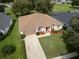 Aerial view of a well-maintained home featuring a manicured lawn, vibrant landscaping, and an attached garage at 16627 Rockwell Heights Ln, Clermont, FL 34711