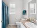 Bright bathroom with a single sink, toilet, and shower-tub combo with a blue curtain at 16627 Rockwell Heights Ln, Clermont, FL 34711