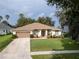 Charming single-story home boasts a manicured front lawn, mature landscaping, and a two-car garage at 16627 Rockwell Heights Ln, Clermont, FL 34711