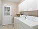 Bright laundry room features tile flooring, a utility sink, washer, dryer, and white storage cabinets at 17764 Se 95Th Ct, Summerfield, FL 34491