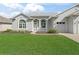 Front exterior showcasing the well-kept lawn, arched windows, and attached two-car garage at 17899 Se 115Th Cir, Summerfield, FL 34491