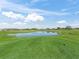 Scenic view of a lush golf course with a beautiful pond reflects a clear blue sky and fluffy white clouds at 17899 Se 115Th Cir, Summerfield, FL 34491