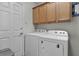 Bright laundry room with a stacked washer and dryer, storage cabinets above, and a door at 1817 Orange Ct, The Villages, FL 32162