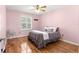 Inviting bedroom featuring a cozy bed, wood floors, and a window with plantation shutters at 2010 Harston Trl, The Villages, FL 32162