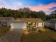 Charming single-story home with a stone driveway, well-manicured lawn, and beautiful landscaping at dusk at 2010 Harston Trl, The Villages, FL 32162