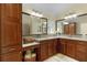 Bathroom with granite countertop, dual sinks, cherry cabinets, and decorative baskets with towels at 2022 Abordale Ln, The Villages, FL 32162