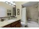 Bathroom featuring granite countertop, dark wood cabinets, and a shower and tub with a shower curtain at 2022 Abordale Ln, The Villages, FL 32162