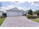 A three car garage home with a brick paver driveway and manicured lawn at 2022 Abordale Ln, The Villages, FL 32162