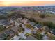 Panoramic aerial shot of a suburban neighborhood at sunset, showcasing a mix of home styles and tree-lined streets at 235 Pima Trl, Groveland, FL 34736