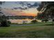 Picturesque lake view with a private boat dock, a charming sunset, and a verdant green lawn at 2422 Topping Pl, Eustis, FL 32726