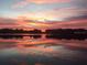 A sunset reflection off lake waters with clouds on the horizon at 2422 Topping Pl, Eustis, FL 32726