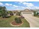 Charming single-story home featuring a manicured lawn, lush landscaping, and a two-car garage at 25073 Riverwalk Dr, Leesburg, FL 34748