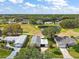 Aerial view of the home, featuring a large pond, surrounding trees, and views of the surrounding community at 25605 Belle Alliance, Leesburg, FL 34748