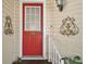 Close-up of a red front door with decorative details and a well-lit entrance, creating an inviting appeal at 25605 Belle Alliance, Leesburg, FL 34748